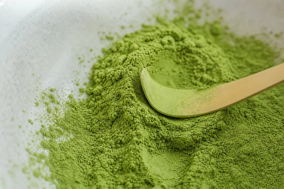 Gros plan sur une poudre de matcha très fine et une cuillère en bambou