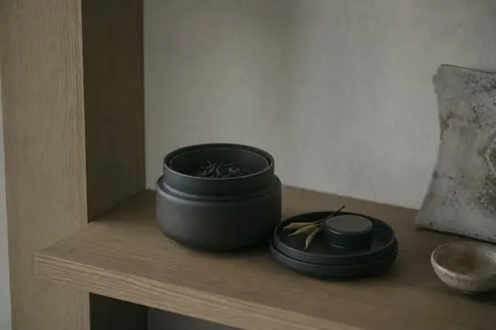 Une boîte à thé à double couvercle ouverte sur une étagère de placard à l’abri de la lumière
